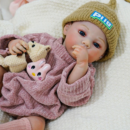 Reborn baby doll cuddling a teddy bear while resting in a pink outfit.