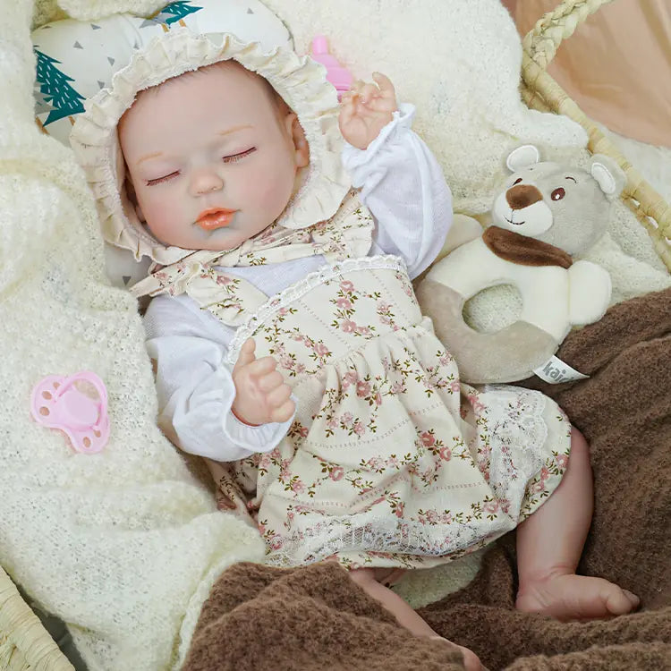 Reborn baby doll in a floral bonnet and dress, sleeping peacefully in a basket, cuddled by plush blankets and a teddy bear, exuding a serene nursery atmosphere.