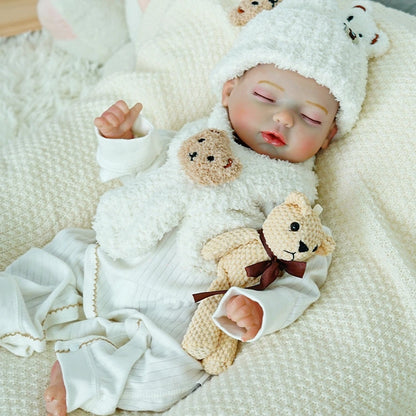 Reborn baby doll wearing a bear hat, lying on a white blanket.