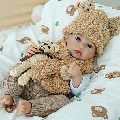 Reborn baby doll lying on the side, dressed in a bear outfit, holding a teddy bear.