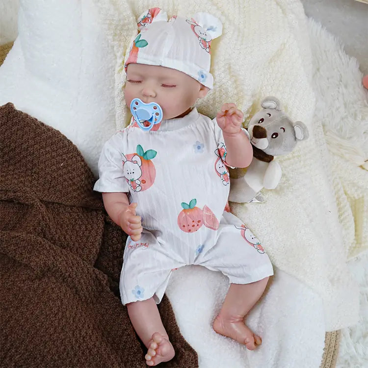 Sleeping newborn doll with soft fruit motif clothing and headband.
