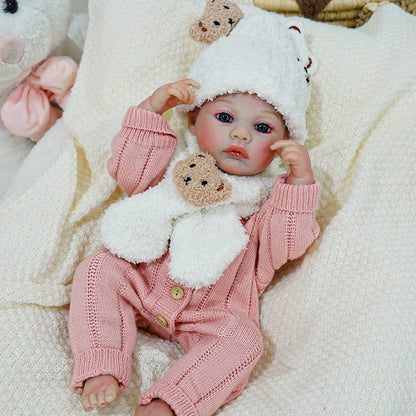 Reborn baby doll adjusting its bear-themed hat, looking sweet and cozy.