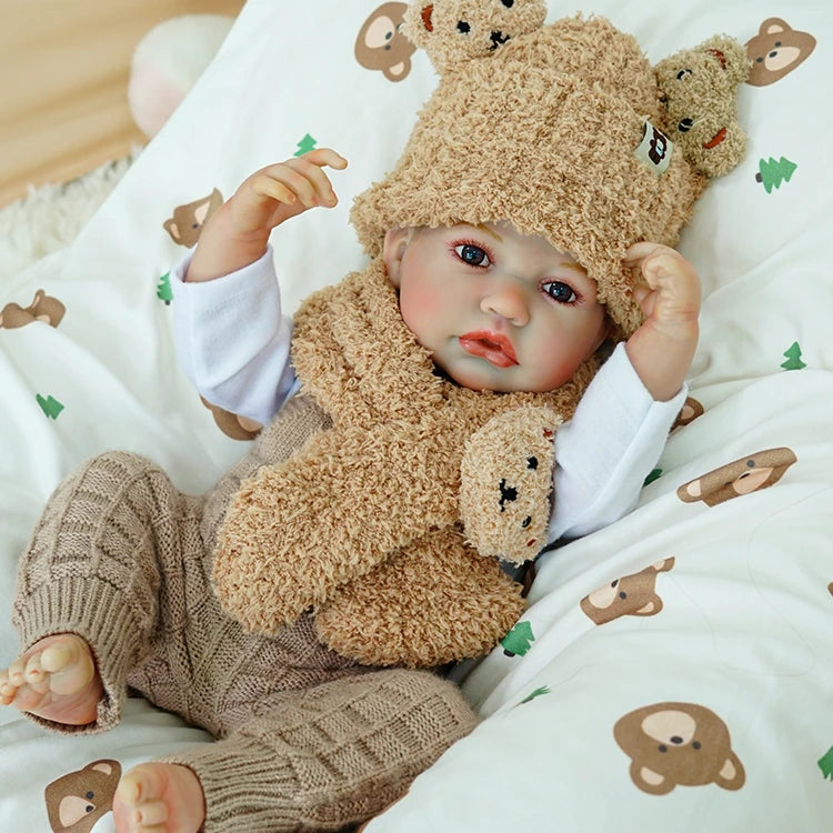 Reborn baby doll with a bear hat, posing cutely.