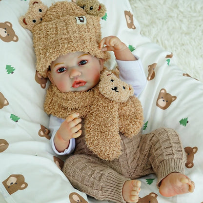 Reborn baby doll lying on its back, holding a plush toy, dressed in adorable clothes.