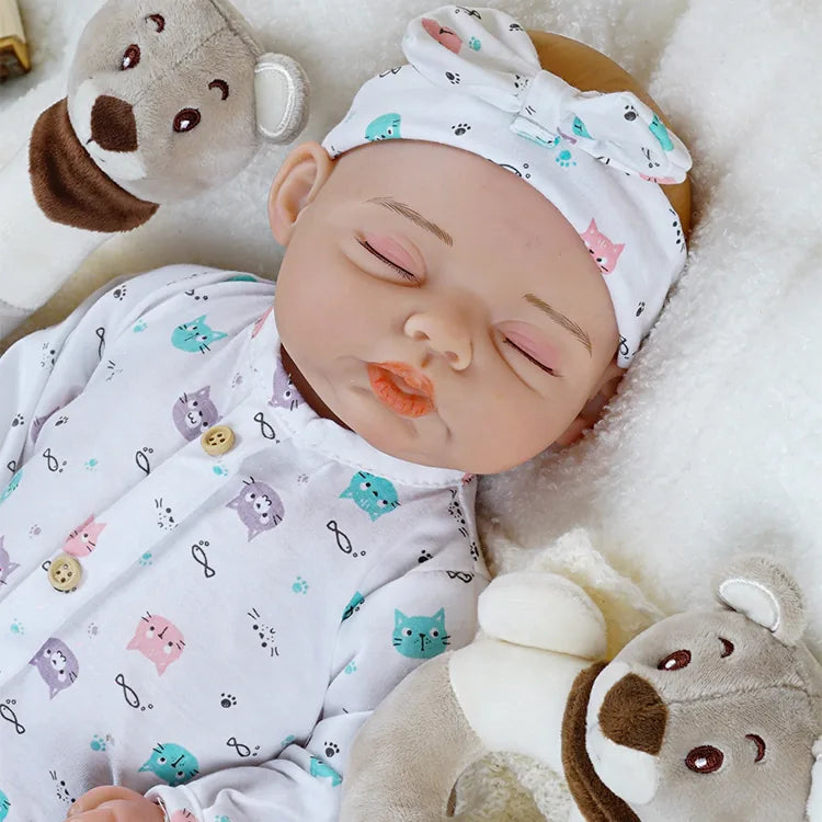 Lifelike reborn doll lying on a soft blanket, holding a plush bear toy, showcasing realistic baby features.