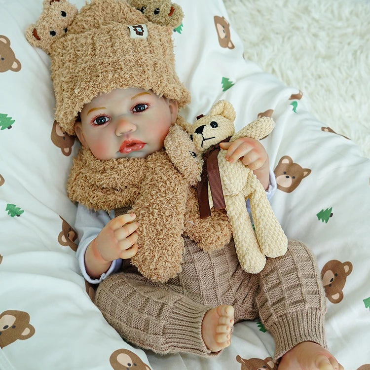 Reborn baby doll on the bed, wearing warm, fluffy clothes.