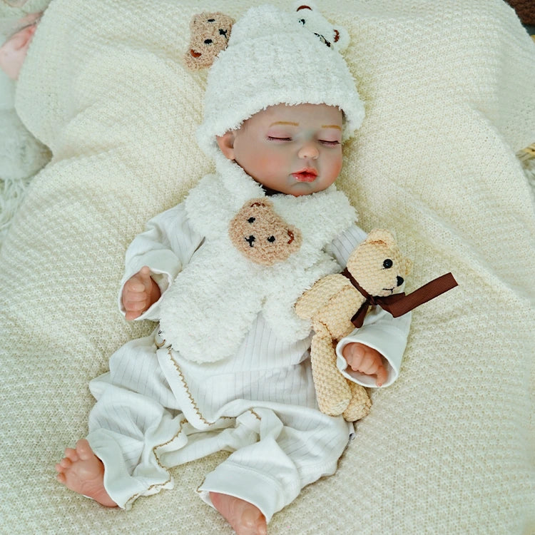 Reborn baby doll lying peacefully, wearing a fluffy white outfit.