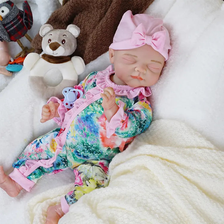 A close-up of the first baby doll's face with the pink headband, showcasing her peaceful sleeping expression with a subtle smile.