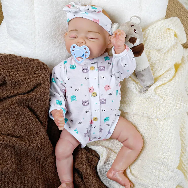 Handmade sleeping reborn doll with poseable features, wearing a patterned onesie and a head wrap, perfect for birthday presents.