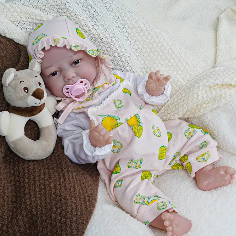 A cute reborn baby doll with a pink pacifier lying on the sofa