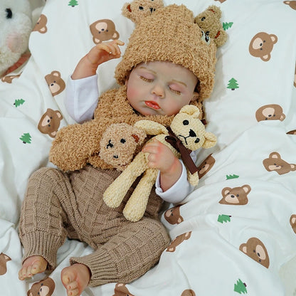 Reborn baby doll raising its hand while resting with a teddy bear.
