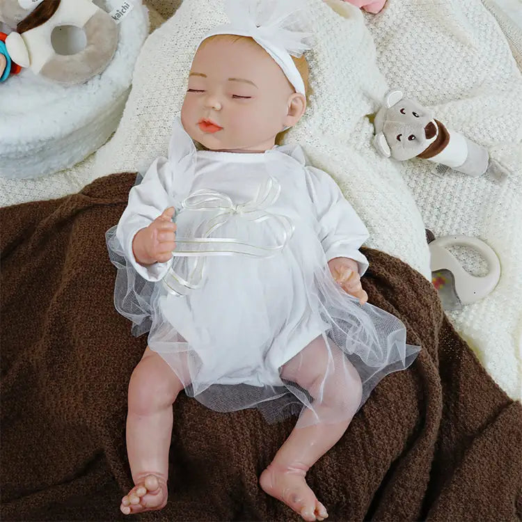 Newborn baby doll attired in white christening dress.