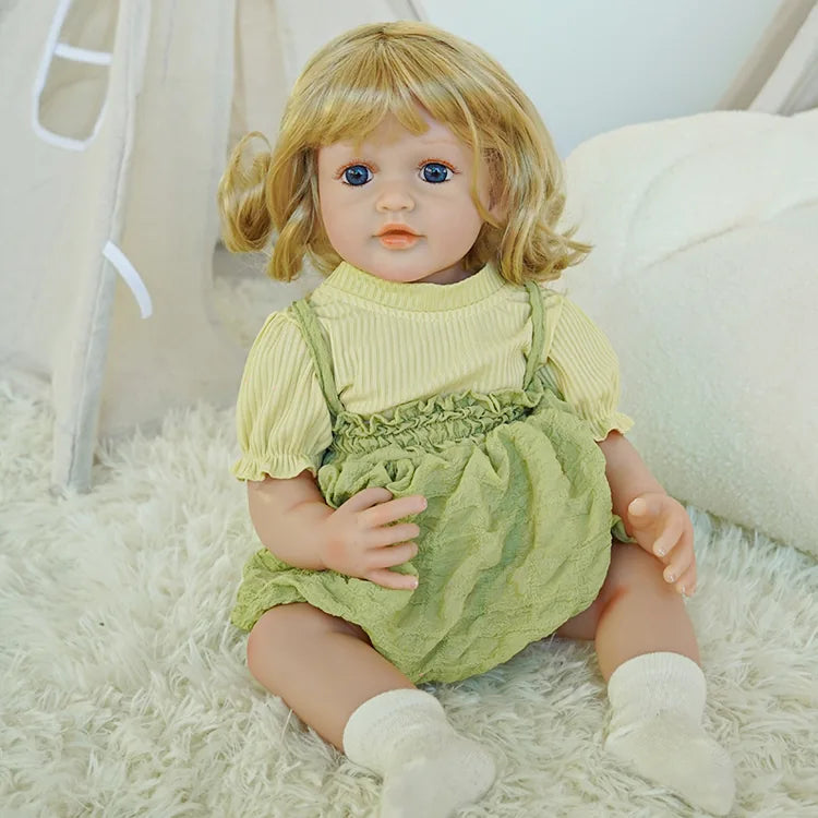  The same reborn baby doll is sitting on a carpet, showing a full-body pose, wearing the same light yellow top and green dress with white socks, looking natural.