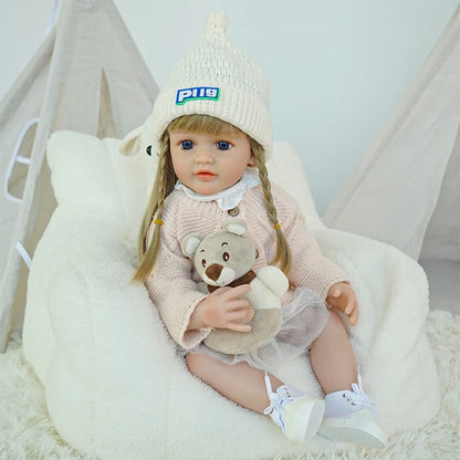  Reborn doll in pink sweater and white skirt, holding a teddy bear.