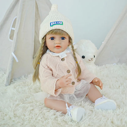 Reborn doll sitting on a carpet, with a tent and toy lamb in the background.