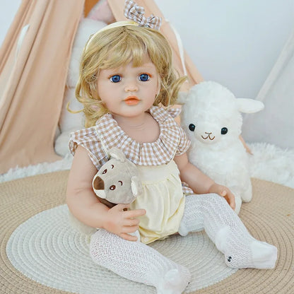 Reborn Toddler Doll holding a bear, sitting on a rug, with a gentle expression.