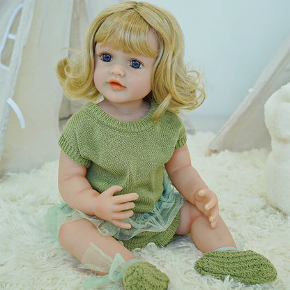 Close-up of reborn doll with blonde hair in a green dress.