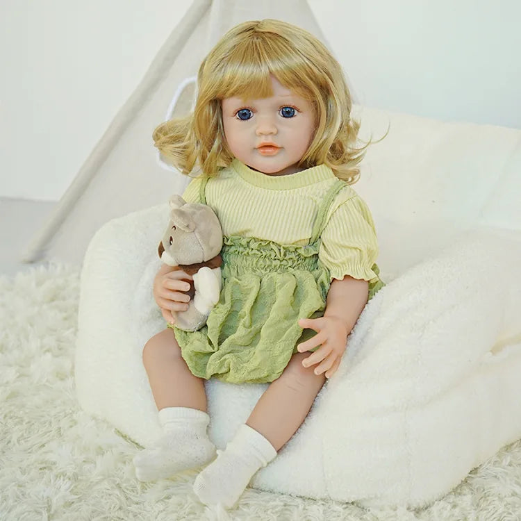 The reborn baby doll is sitting on a soft cushion, with hands naturally placed, showing her adorable pose in a different background.