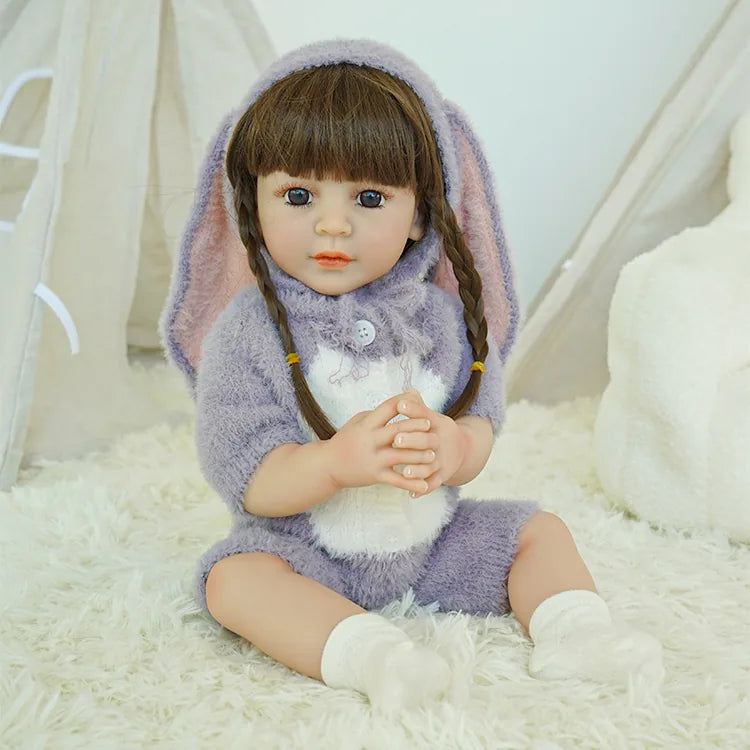 Reborn doll in purple bunny outfit, hands clasped together.