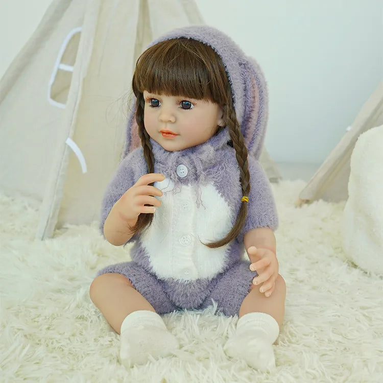 Reborn doll in purple bunny outfit, sitting on the carpet, looking to the side.