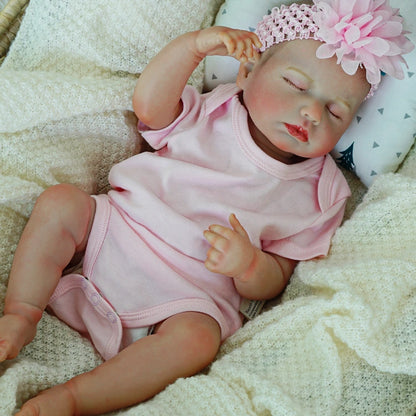 Reborn baby doll with arms up, relaxed and sleeping.