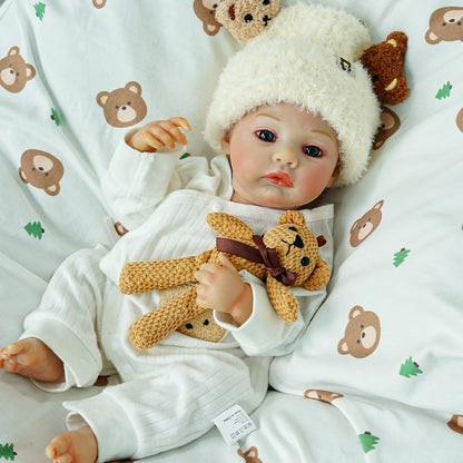 Reborn doll looking up while holding the teddy bear.