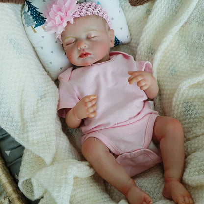 Lifelike reborn baby doll lying in a pink onesie.