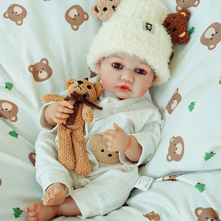 Doll sitting up, holding a teddy bear and gazing forward.