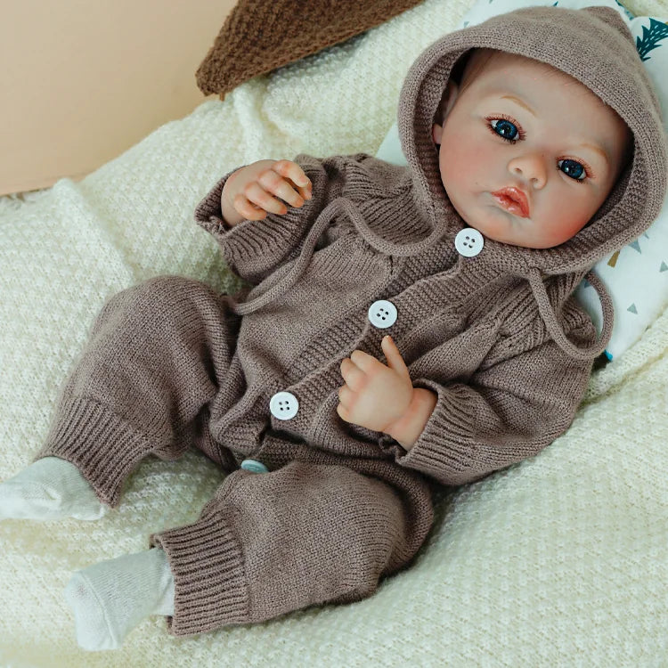 Reborn doll in a brown knit outfit with hood.