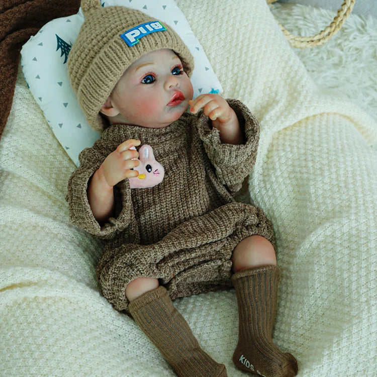 Reborn doll holding a plush bunny, dressed in a cozy brown outfit.