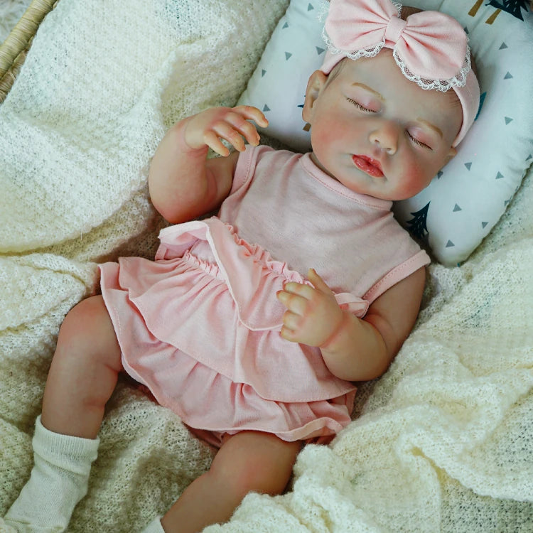 Lifelike reborn doll sleeping peacefully in a pink outfit.