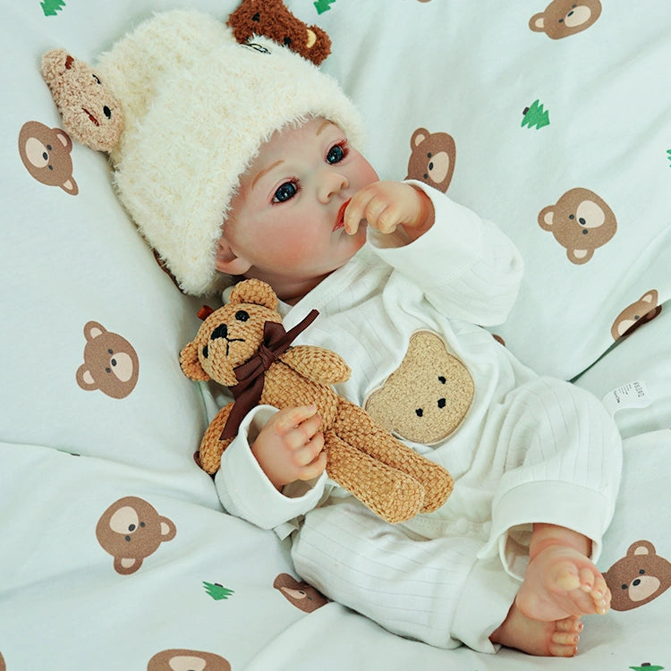 Close-up of the reborn doll holding a teddy bear.