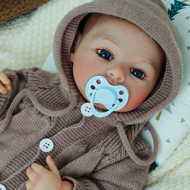 Reborn baby doll with a pacifier, wearing a knit hoodie.