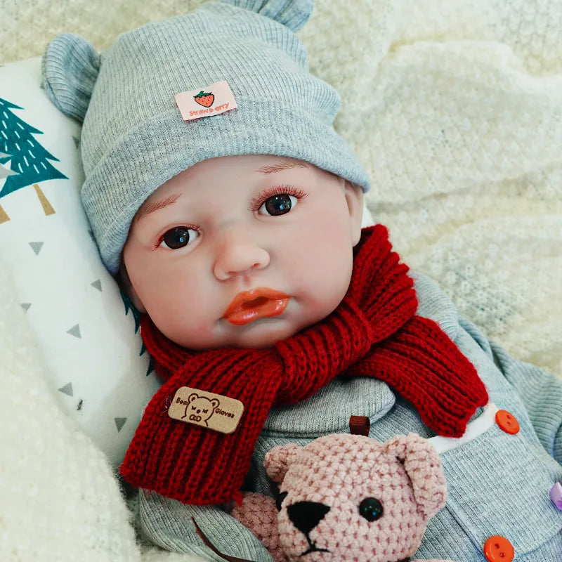 Close-up of the reborn baby doll's face, showing off its lifelike features while holding a teddy bear.