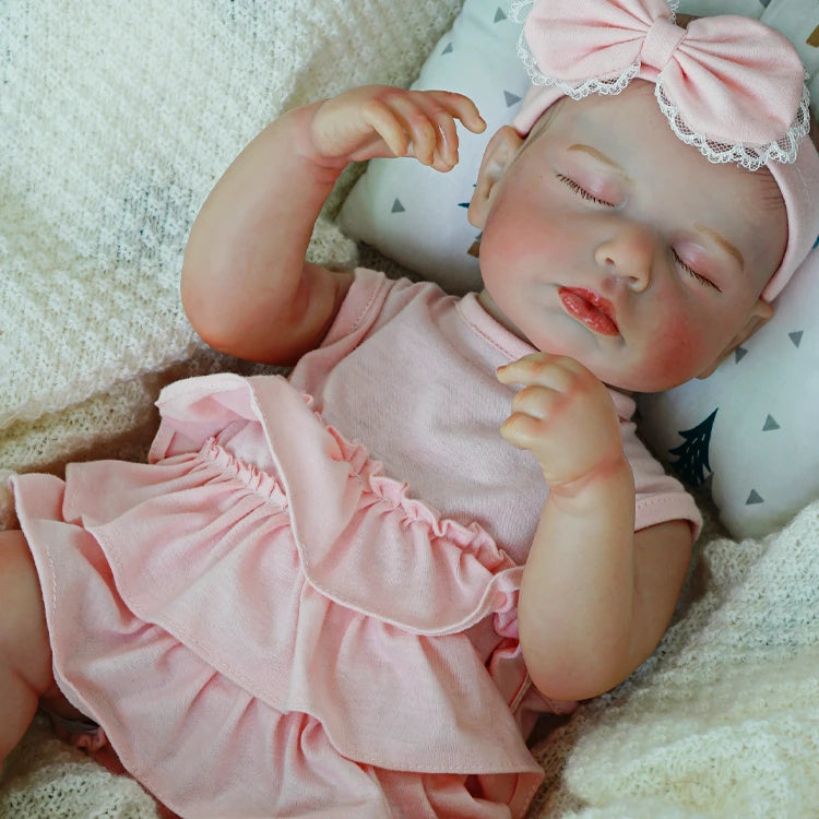 Reborn baby doll resting in a ruffled pink dress