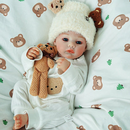 Reborn doll reclining with hands behind the head and holding a teddy bear.