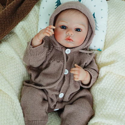 Reborn doll raising arm while dressed in brown