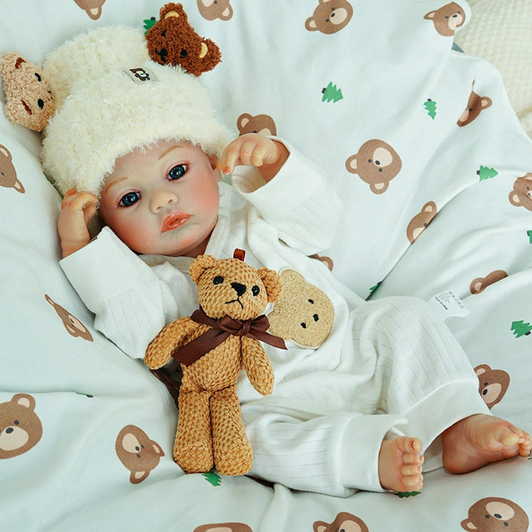 Reborn doll sitting comfortably with the teddy bear.