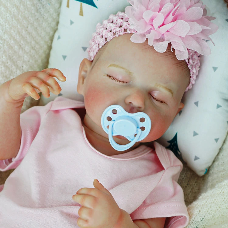 Reborn baby doll with a pacifier and pink flower headband.