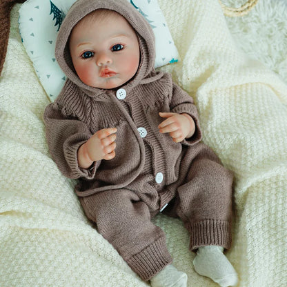 Close-up of reborn baby doll with brown knit outfit.