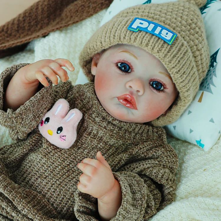 Reborn doll sitting in a soft blanket, holding a plush bunny.