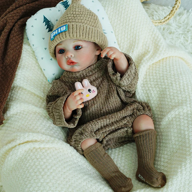 Reborn doll with a pacifier, dressed in a brown knit outfit.