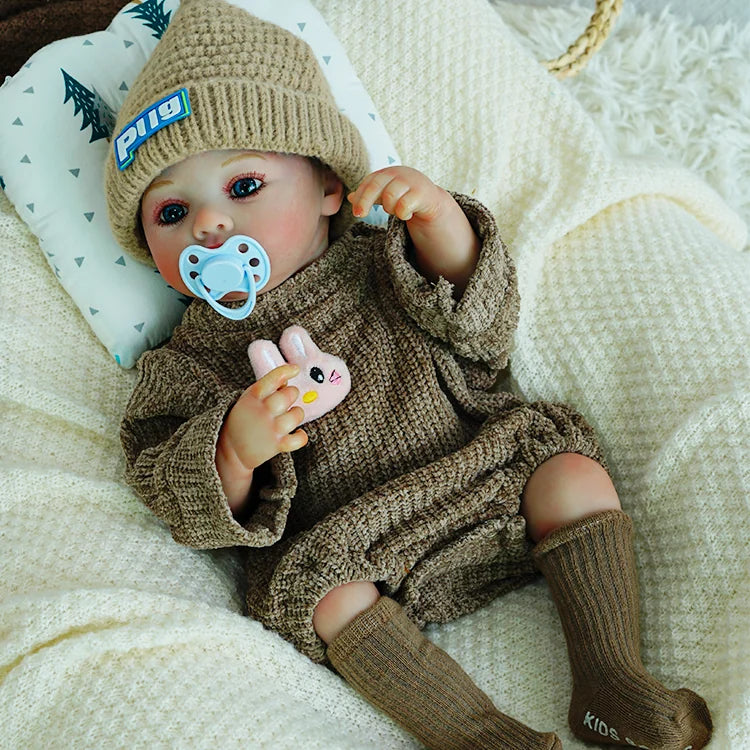 Reborn doll wearing a brown outfit with a knit hat and plush bunny.