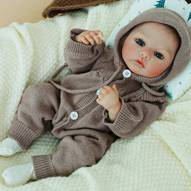 Reborn doll posing in a brown knit hoodie.