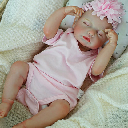 Peacefully resting reborn baby doll with hands raised.