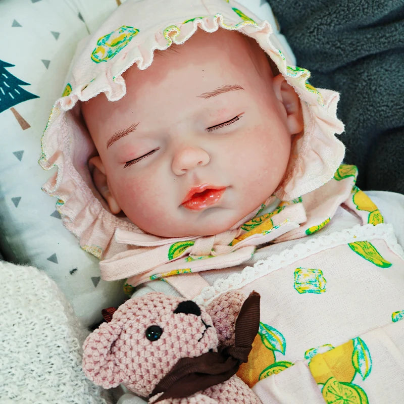 The reborn baby doll sleeping soundly in a green patterned onesie, cuddling with its knitted bear.