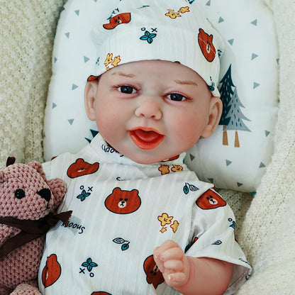 The reborn baby doll with a joyful expression, dressed in a white animal print onesie, sitting comfortably with a knitted teddy bear.