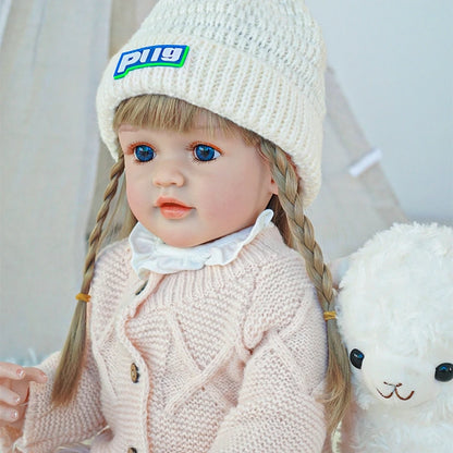 Close-up of a reborn toddler doll with braided hair, wearing a pink coat and knit hat.