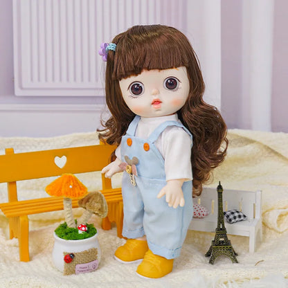 A charming doll in a white blouse and soft blue dungarees decorated with a plush bear, near a model of the Eiffel Tower.